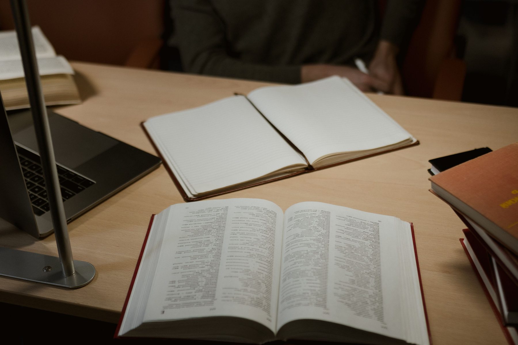 Ahşap masa üzerinde defter ve kitaplar; temsili stok görsel.